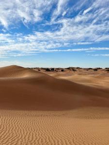 um deserto com dunas de areia e um céu azul em Chegaga Luxury Camp em El Gouera