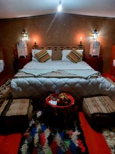 a bedroom with a large bed with two lights on the wall at Chegaga Luxury Camp in El Gouera