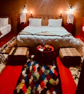 a bedroom with a large bed with a colorful rug at Desert Chegaga Luxury Camp in El Gouera