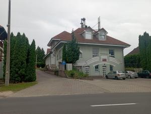 une grande maison avec des voitures garées devant elle dans l'établissement Kata Apartman Siófok, à Siófok