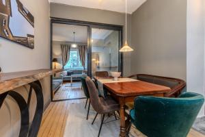 a dining room with a wooden table and green chairs at Eternity Apartment: Award-Winning Design in the Heart of the City Center in Sofia