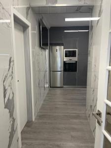 a hallway of a kitchen with a stainless steel refrigerator at Coração de Furadouro in Ovar