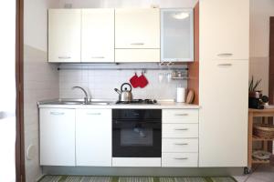 una cocina con armarios blancos y fregadero en Bell Tower Apartament in Aviano en Aviano