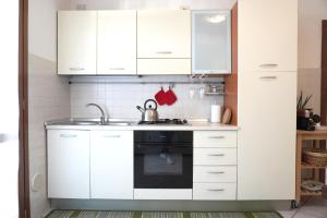 een keuken met witte kasten en een wastafel bij Bell Tower Apartament in Aviano in Aviano