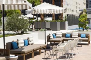 un patio con sofás, sillas y una sombrilla en Level Los Angeles - Downtown South Olive en Los Ángeles