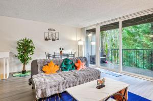 a living room with a couch and a table at Lake Oswego Condo with Balcony, 3 Mi to the Water! in Lake Oswego