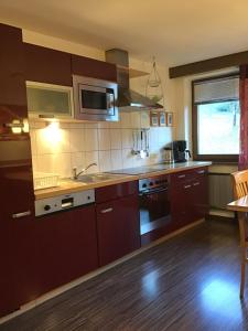 - une cuisine avec des placards bruns et un four micro-ondes dans l'établissement Alpbach Apartments, à Reith im Alpbachtal