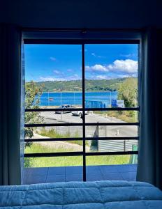 1 dormitorio con una gran ventana con vistas al océano en Hostal Umantun, en Dalcahue