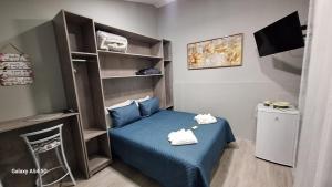 a small room with a blue bed and a shelf at Pousada Kekas in Duque de Caxias