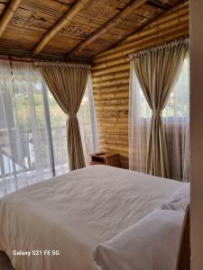1 dormitorio con 1 cama y ventanas grandes en De Bambú Guatavita, en Guatavita