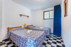 twee bedden in een kamer met een geruite vloer bij Apartamento Bilo 302 in Es Pujols