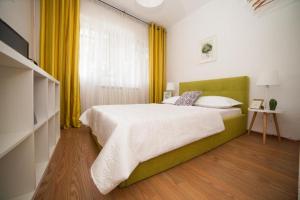 Guesthouse Smart في بوخارست: غرفة نوم بسرير كبير وستائر صفراء