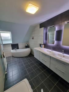 łazienka z 2 umywalkami i wanną w obiekcie Le gîte de Cléo, maison spacieuse et paisible. w mieście Metzeral