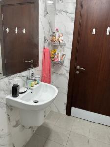 a bathroom with a white sink and marble walls at LADIES ONLY - BED IN THE ROOM - Near Metro Station in Dubai