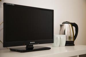 a computer monitor sitting on a desk with a coffee pot at Guesthouse Smart Rooms Bucharest in Bucharest