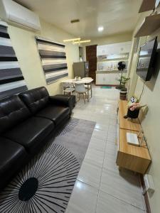a living room with a black leather couch and a table at 2 Bedroom Guest Suite Near The New EVRMC Hospital & San Juanico Bridge Tacloban City, Leyte, Philippines in Tacloban