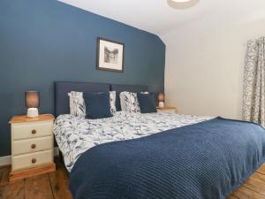 a blue bedroom with a bed with a blue wall at 1 Tump Cottages in Hereford