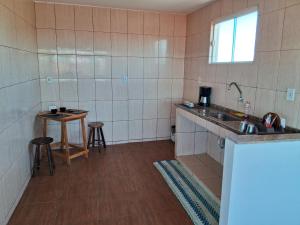 eine kleine Küche mit einem Waschbecken und einem Tisch in der Unterkunft CABO FRIO, SUITES PÉ AREIA in Cabo Frio
