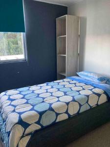 Schlafzimmer mit einem Bett mit einer blauen und weißen Bettdecke in der Unterkunft Departamento amoblado en Constitución in Constitución