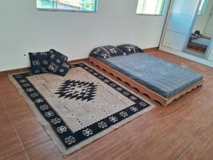 uma cama com almofadas e um tapete no chão em CABO FRIO, SUITES PÉ AREIA em Cabo Frio