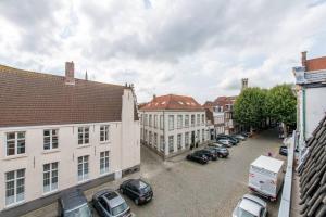 une rue de la ville avec des voitures garées dans un parking dans l'établissement Suite Stays Bruges, à Bruges