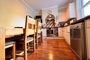 a kitchen with a table and chairs and a clock on the wall at Two Bedroom Period Property in Tivoli Cheltenham in Cheltenham