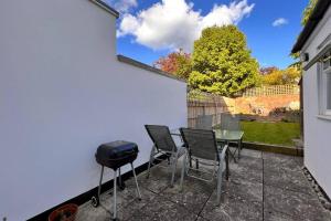 a patio with a table and chairs and a grill at Two Bedroom Period Property in Tivoli Cheltenham in Cheltenham