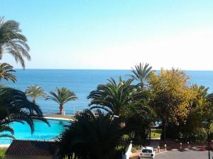 Blick auf einen Pool mit Palmen und das Meer in der Unterkunft Urbanizacion La Roca Estudio in Torremolinos