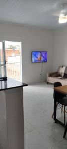 a white living room with a tv on a wall at Pousada Recanto Boituva in Boituva