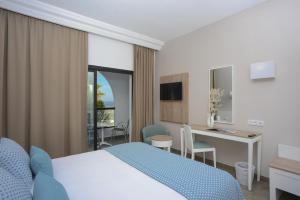 ハンマメットにあるNozha Beach Resort & Spaのベッド、デスク、テーブルが備わる客室です。