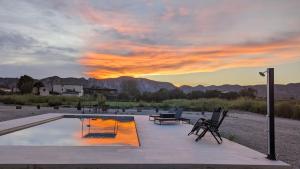 un patio con piscina, sillas y puesta de sol en MASIA CLOTATS, en Gerp