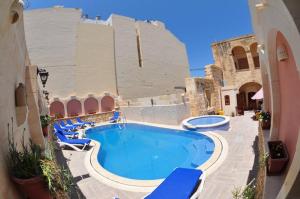 una piscina con sedie blu e un edificio di 6 Bedroom Farmhouse with Private Pool in Zebbug Gozo a Żebbuġ