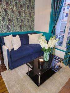 French Luxury Paris في باريس: أريكة زرقاء في غرفة المعيشة مع طاولة