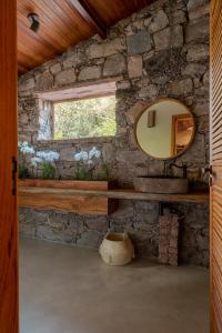 La salle de bains est pourvue d'un miroir et d'un mur en pierre. dans l'établissement Refúgio na Serra Boutique Hotel, à Mucugê