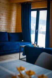 un soggiorno con un divano blu e una grande finestra di Widokowe Stodoły balia z hydromasażem na wylączność a Chyżówki