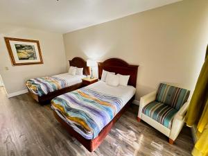 a hotel room with two beds and a chair at Americas Hotel - El Paso Airport / Medical Center in El Paso