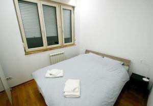 um quarto com uma cama branca com duas toalhas em Monet Business Grade Apartment: ideal for Digital Nomads, MedTourist, Wellness em Belgrado