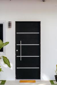 a black door in a white room with a plant at Casa Valencia 2 in Santa Elena