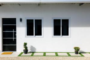 a white house with two windows and two potted plants at Casa Valencia 2 in Santa Elena