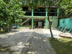 ein grünes Gebäude mit einem Baum davor in der Unterkunft casa indisponivel in Caraguatatuba