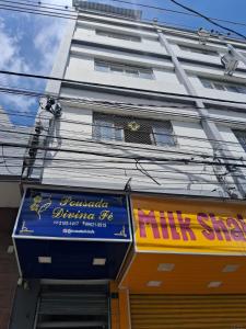 a white building with a sign for a nail shop at Pousada Divina Fé in Aparecida