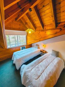 2 bedden in een kamer met houten plafonds bij Cabaña Oasis in San Martín de los Andes