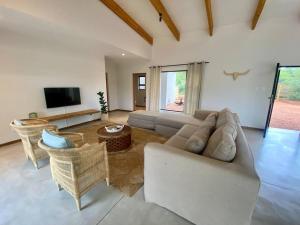 a living room with a couch and chairs and a tv at Corkwood Villa in Hoedspruit