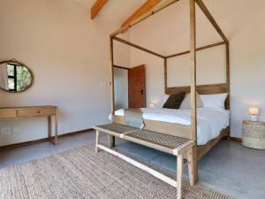 um quarto com uma cama de dossel e um banco em Corkwood Villa em Hoedspruit