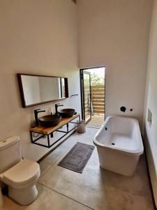 a bathroom with a tub and a toilet and a sink at Corkwood Villa in Hoedspruit