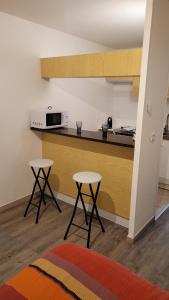 uma cozinha com dois bancos em frente a um balcão em Grand studio confortable jusqu'à 4 personnes em Digne-Les-Bains
