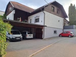 dos autos estacionados en un estacionamiento frente a una casa en LOFT im Erdgeschoss, 45m², Kreuzbergl (1-3 Gäste), en Klagenfurt