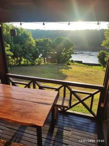 a wooden bench on a porch with a view of the water at Cabaña del rio Paraná in Puerto Iguazú
