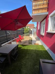 eine Terrasse mit einem Tisch und einem roten Regenschirm in der Unterkunft Maison rouge in Millau
