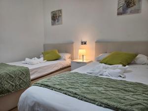 a bedroom with two beds with green sheets and a lamp at 127A Apartamento 3 habitaciones cerca de la playa in Gijón